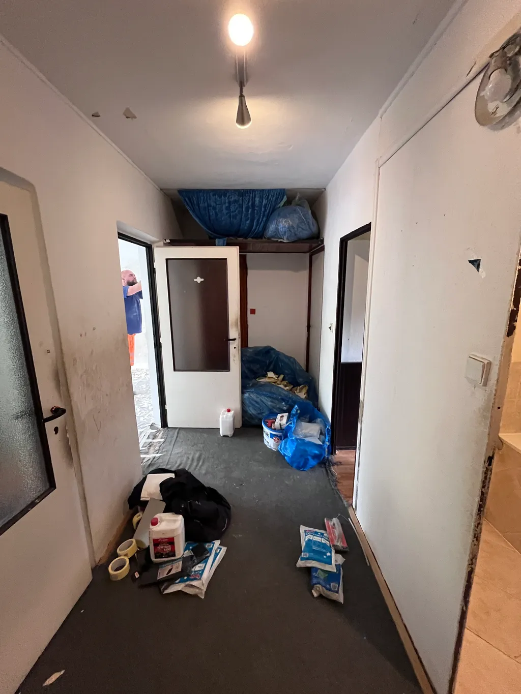 Chodba bytu během vyklízení, připravené pytle a úklidové prostředky